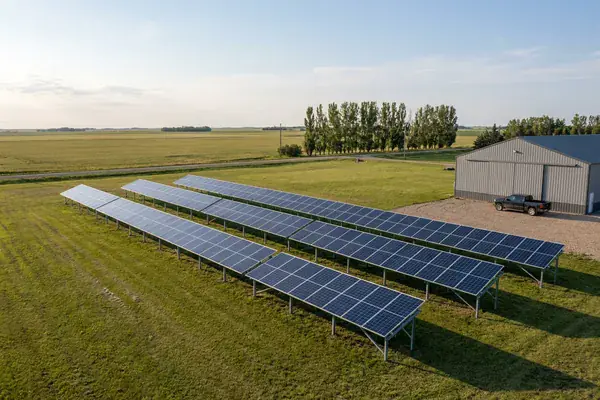 Ground-mounted solar array beside a farm outbuilding